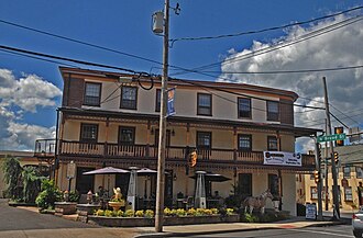 The front of an inn, three stories high, with a balcony on the second floor.