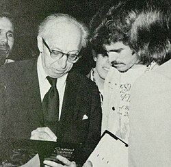 Man wearing glasses and a suit on the left next to another man