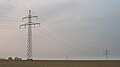 Suspension towers with garland-like communication cable on the ground conductor