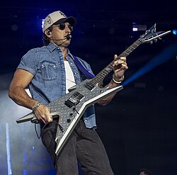 A caucasian man on stage playing guitar