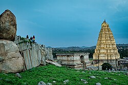 Panoramic high-angle view of the Virupaksha Temple complex and the surrounding boulder-strewn landscape of Hampi, seen from a nearby hilltop.