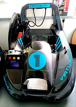 The sit-down version of the Virtuality arcade unit. The unit is a seat with two fixed position joysticks either side for game control. The headset is mounted on a hook.
