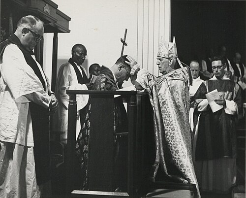 kneeling man being blessed by standing man, the latter in cope and mitre