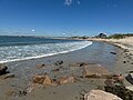 View of East Matunuck State Beach looking west from the east end by the breakwater. It shows the houses along the first part of the beach and the public pavilion in the distance.