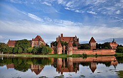 A large walled brick fortress with towers and inner castles on a river