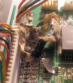 An exploded electrolytic capacitor, showing fragments of paper and metallic foil