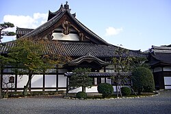 Wooden building with white walls and hip-and-gable style roof.