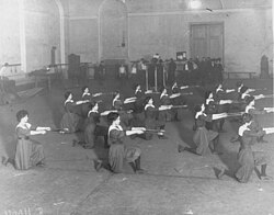 Women kneeling in rows holding out clubs