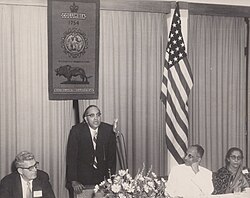 Alumnus B. R. Ambedkar addresses a 1954 seminar in New Delhi in front of a banner showing Columbia's crown, seal, motto, and lion