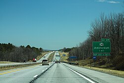 A divided highway with two lanes in each direction, seen on a straightaway with trees off to the sides