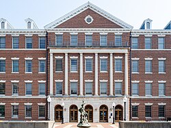 A large Georgian-era style building complete in red brick, classical columns and a statue in front