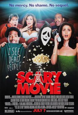 A group of people sitting in a cinema. Among them is a masked figure in black with smiling ghost face mask.