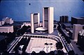 Two curved towers surrounding a circular small building with an open public space in front