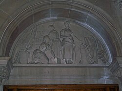  Carved stone tympanum showing mill workers at the loom with a sheet of finished cloth